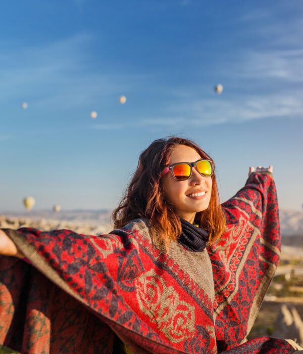 Witness the magic of a tourist girl embracing the captivating sunrise and the spectacle of colorful hot air balloons over Cappadocia's landscape. Experience the essence of joyful travel in Turkey.