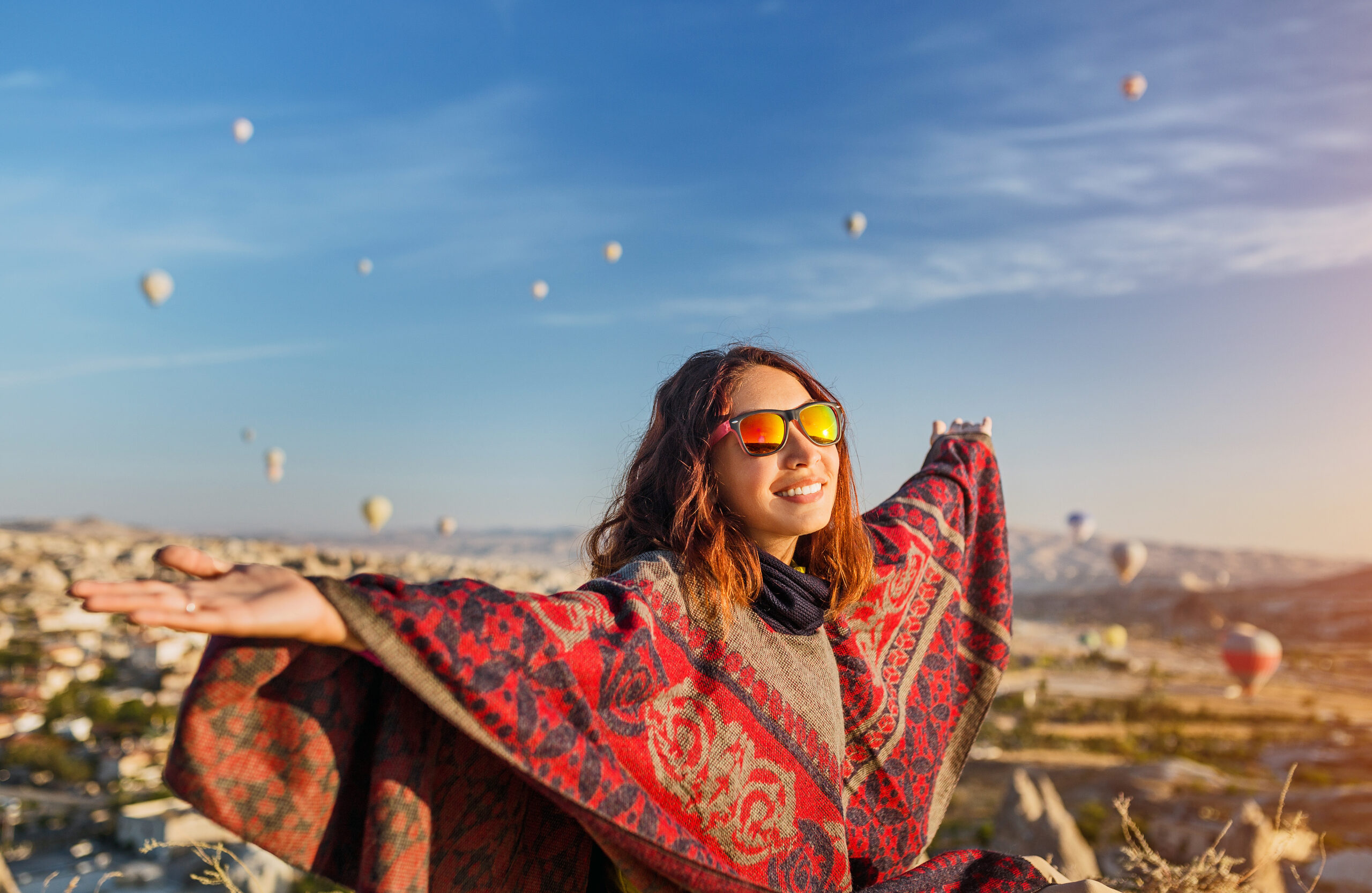 Witness the magic of a tourist girl embracing the captivating sunrise and the spectacle of colorful hot air balloons over Cappadocia's landscape. Experience the essence of joyful travel in Turkey.